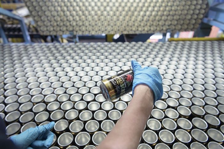 Hands holding aluminium can over rows of cans