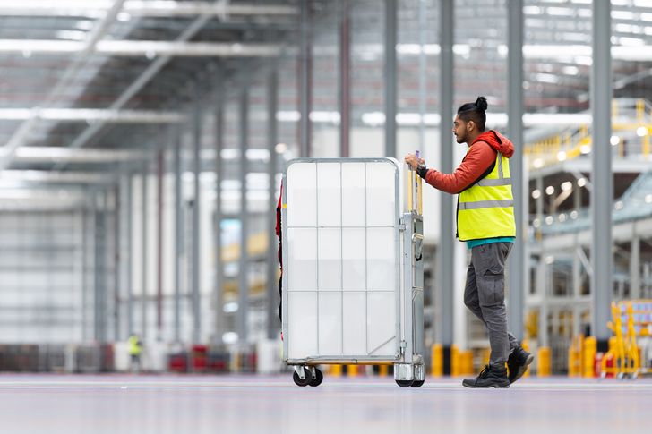 Worker pushing Royal Mail warehouse trolley incorporating new reusable sleeves