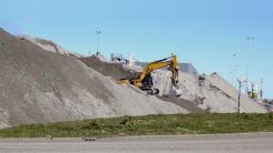Piles of bottom ash from a waste recycling factory to be used in construction instead of sand.