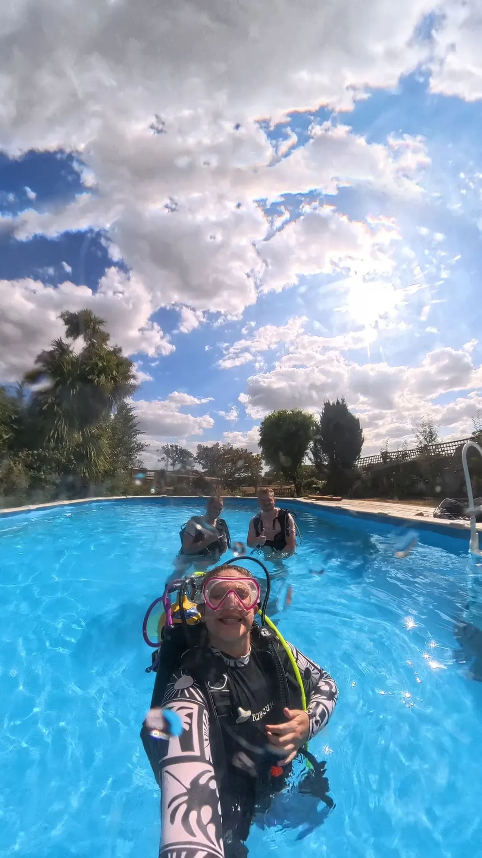 Three of us kitted up in a garden swimming pool on a sunny day