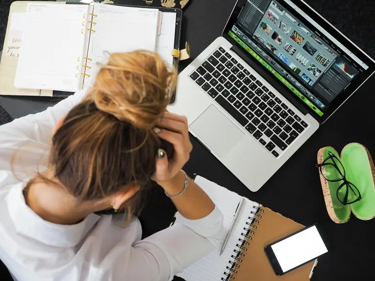 Professional woman in front of laptop with head in hands