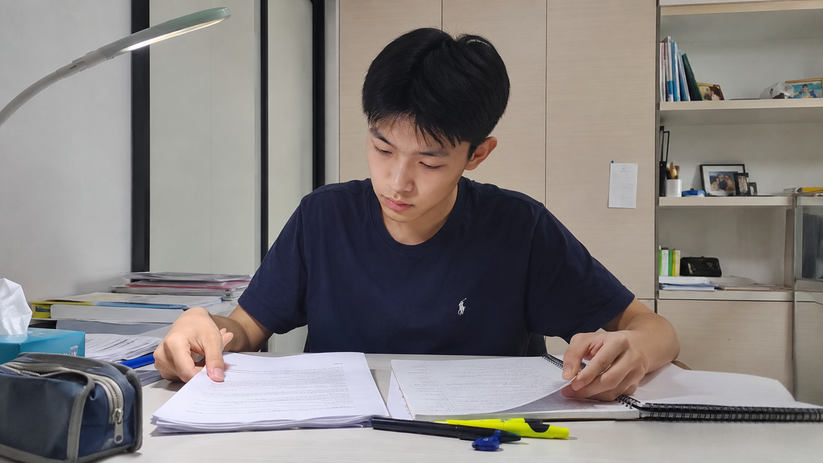 An O-Level English student comparing argumentative and discursive essay conclusions at a study desk