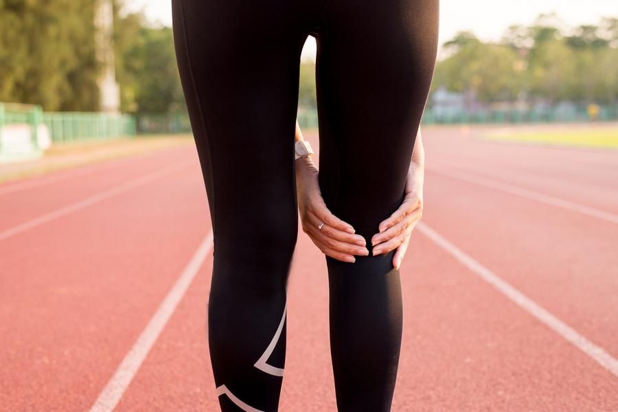 Female runner holds knee as if in pain with ACL injury
