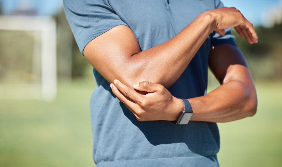 Man holds elbow in pain after elbow injury