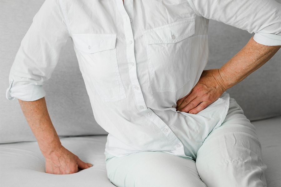 Seated woman holds hip in pain and needs hip pain doctor in San Francisco