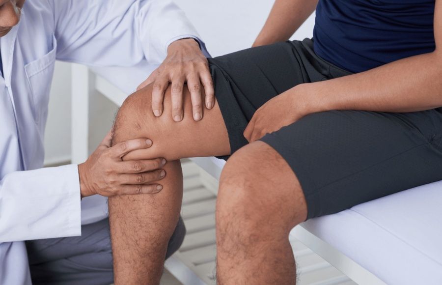 Orthopedic specialist examining a patient’s knee during a consultation for knee pain and instability, highlighting evaluation and care by the best orthopedic doctor for joint replacement revision surgery.