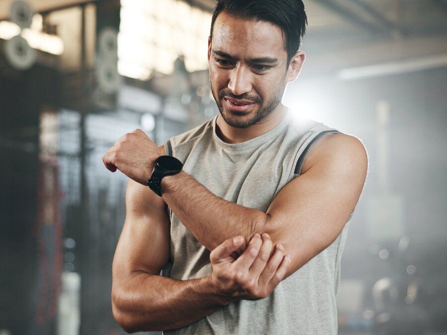 Man athlete holds elbow in pain suffers Tommy John injury