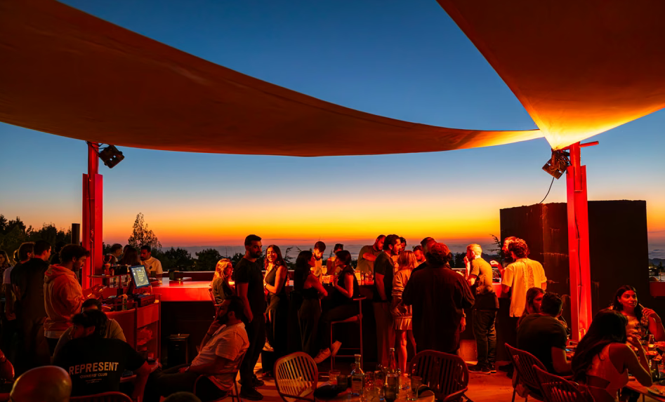 Crowded dance floor overlooking valley at sunset