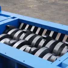 Close-up looking down into an open TASKMASTER TM3000 shredder housing at its twin intermeshing cutter stacks and the row of cleaning combs along the chamber wall.