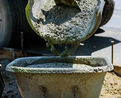 A cement mixer dumping cement into a wheelbarrow