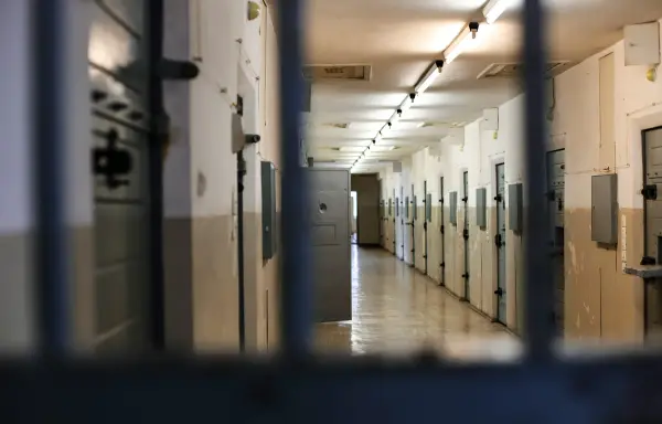 Cell block corridor lined with steel cell doors in a correctional facility