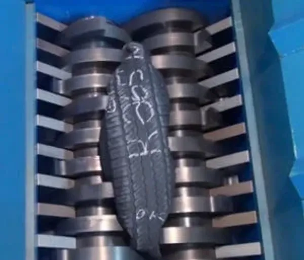 A rubber tire going through an industrial shredder