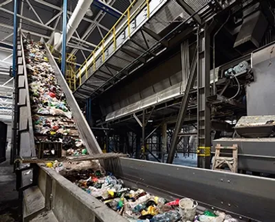 A large conveyor in a warehouse moving piles of recycleable garbage