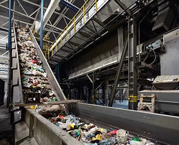 A large conveyor in a warehouse moving piles of recycleable garbage