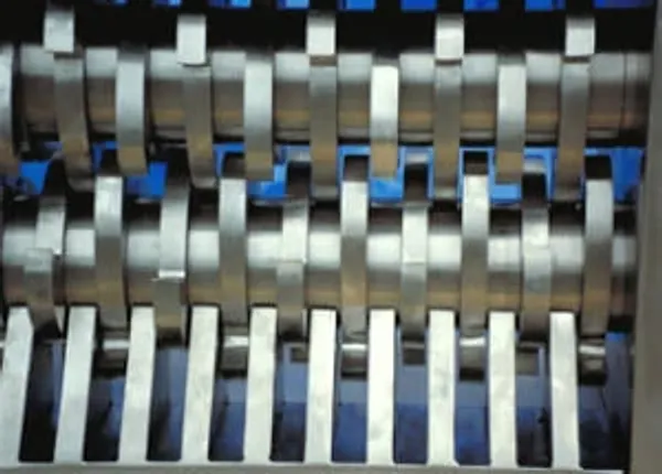 A closeup of the cutting teeth inside of an industrial shredder