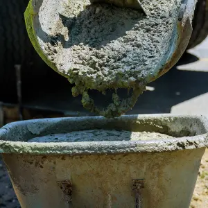 A cement mixer dumping cement into a wheelbarrow