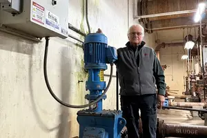 Man standing with an inline wastewater grinder installed in his plant