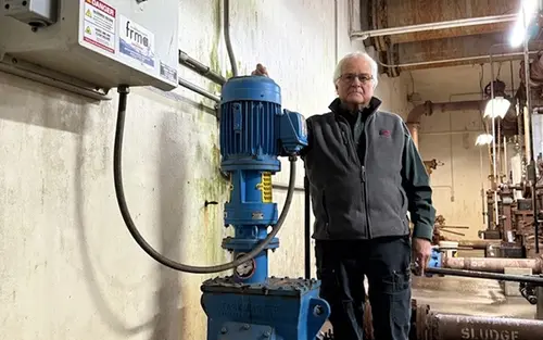 Man standing with an inline wastewater grinder installed in his plant