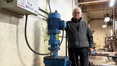 Man standing with an inline wastewater grinder installed in his plant