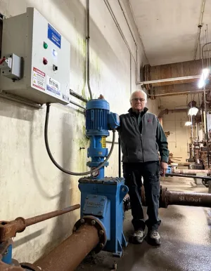 Man standing with an inline wastewater grinder installed in his plant