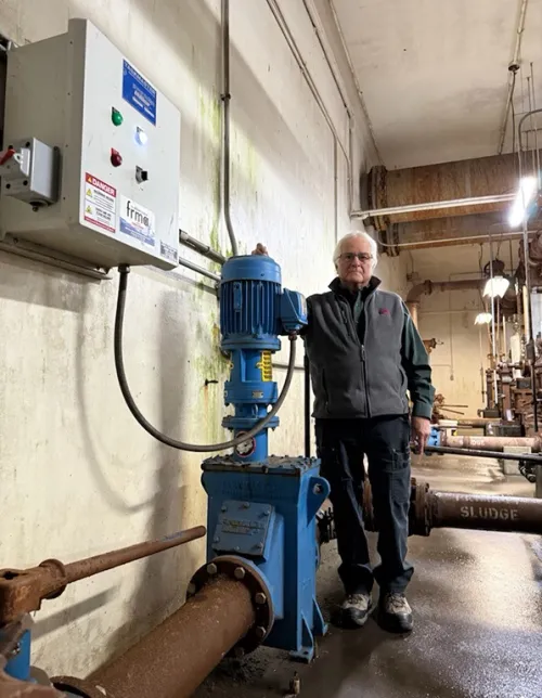 Man standing with an inline wastewater grinder installed in his plant