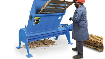 man shredding pallet in blue machine