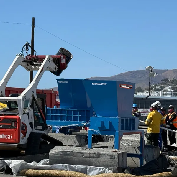 Two shredders being loaded with a barrel of batteries