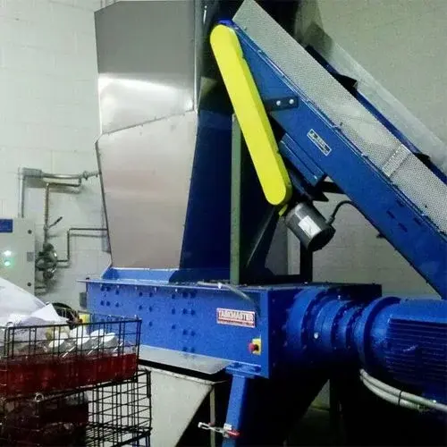 A large industrial shredder with a conveyor attachment in a warehouse