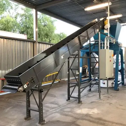 An industrial shredder with a conveyor attached installed at a facility