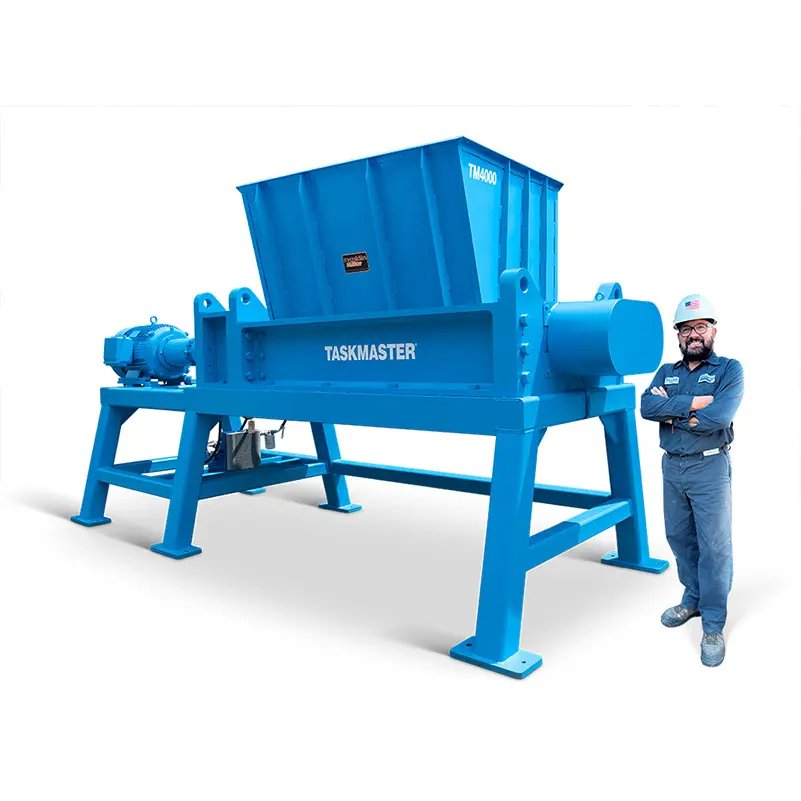 Franklin Miller employee standing beside a large TASKMASTER industrial shredder for scale