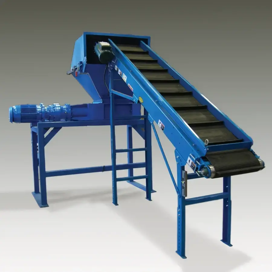 Blue TASKMASTER twin-shaft shredder on a welded stand with a feed hopper on top and an inclined belt conveyor feeding material into the hopper