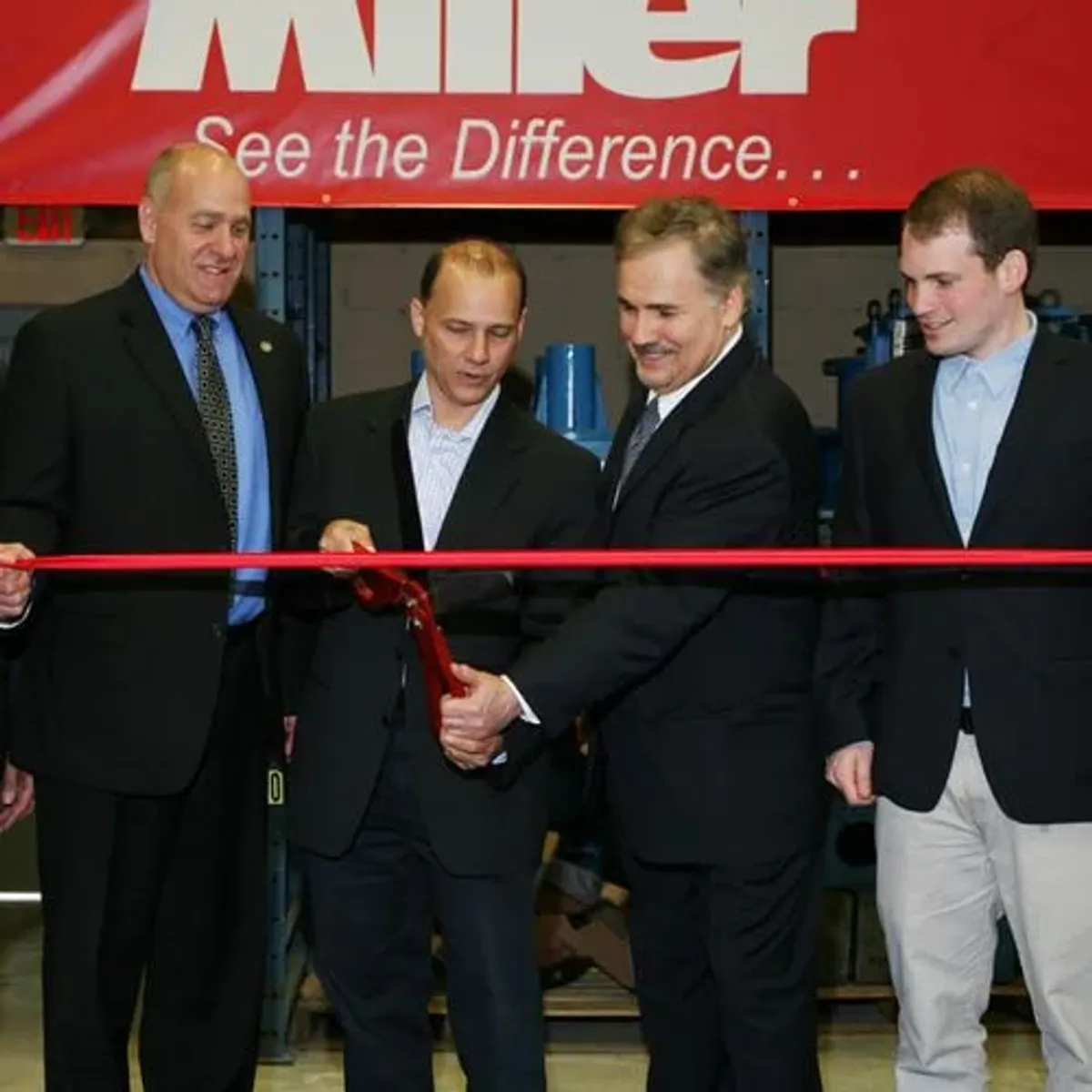 group of men cutting red ribbon