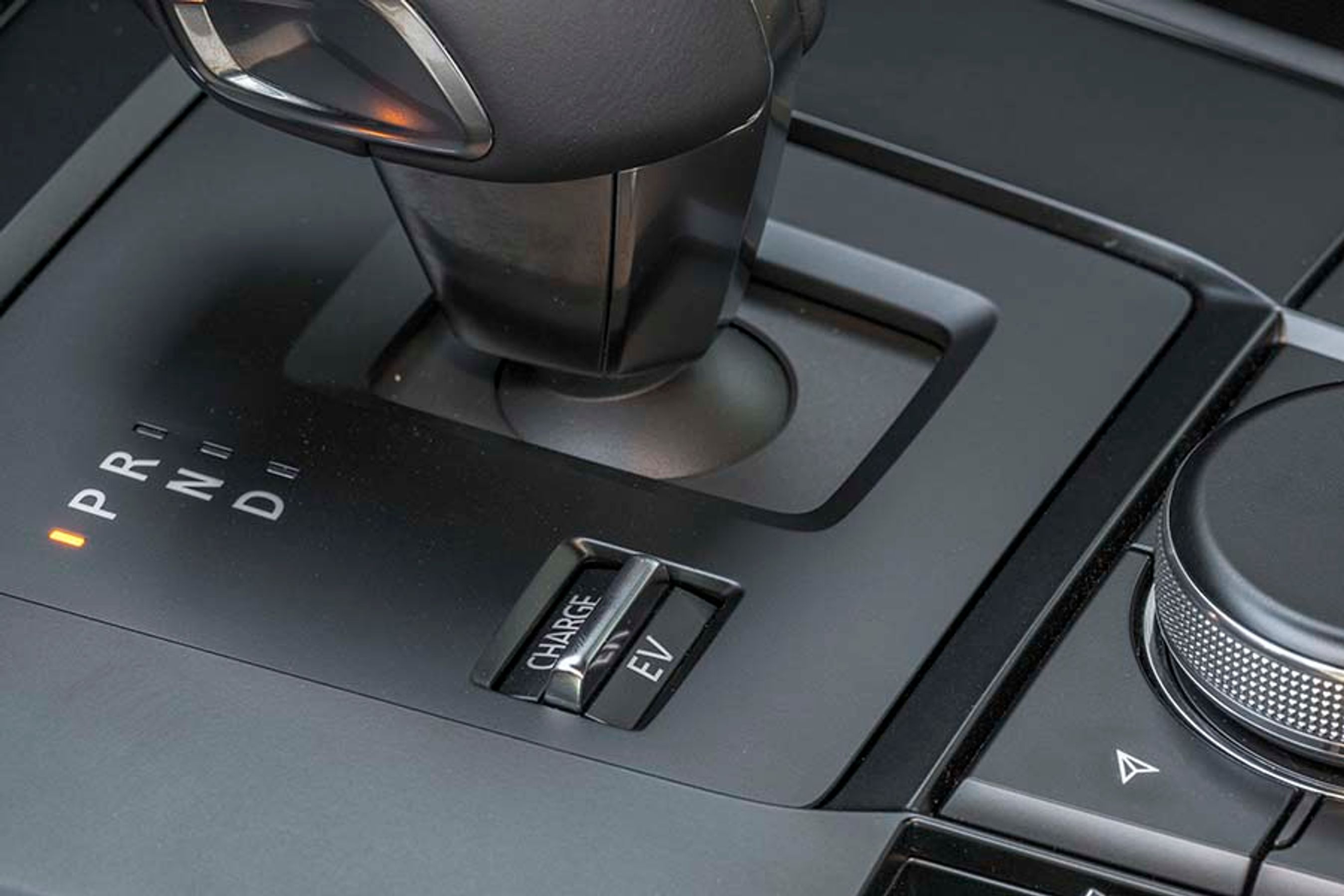 Ved siden af gearvælgeren er en lille knap, hvorfra man kan vælge mellem tre køreprogrammer: Normal, EV og Charge. I Normal prioriteres elkørsel, så længe der er mere end 40 procent på batteriet. I EV kører bilen på el så længe som muligt, og i Charge starter benzinmotoren op og lader på batteriet.