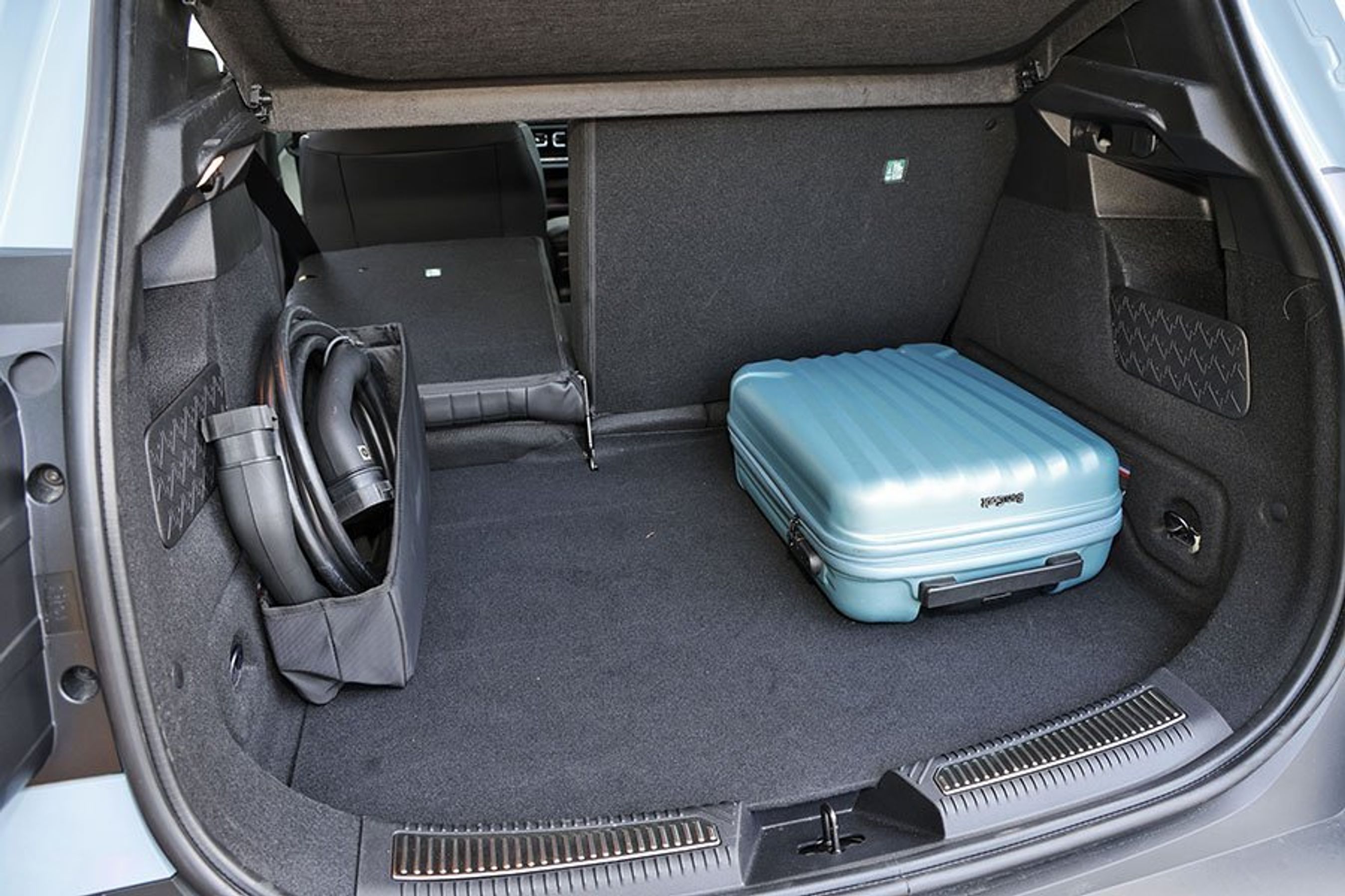 Bagagerum med blå kuffert og ladekabel i en Renault 4