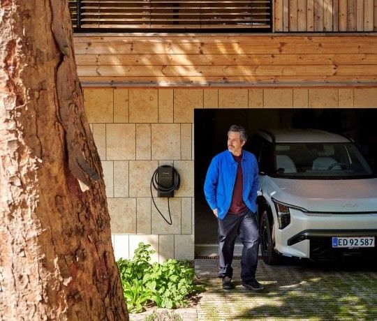 Mand kommer ud af garage med hvid elbil og clever ladeboks