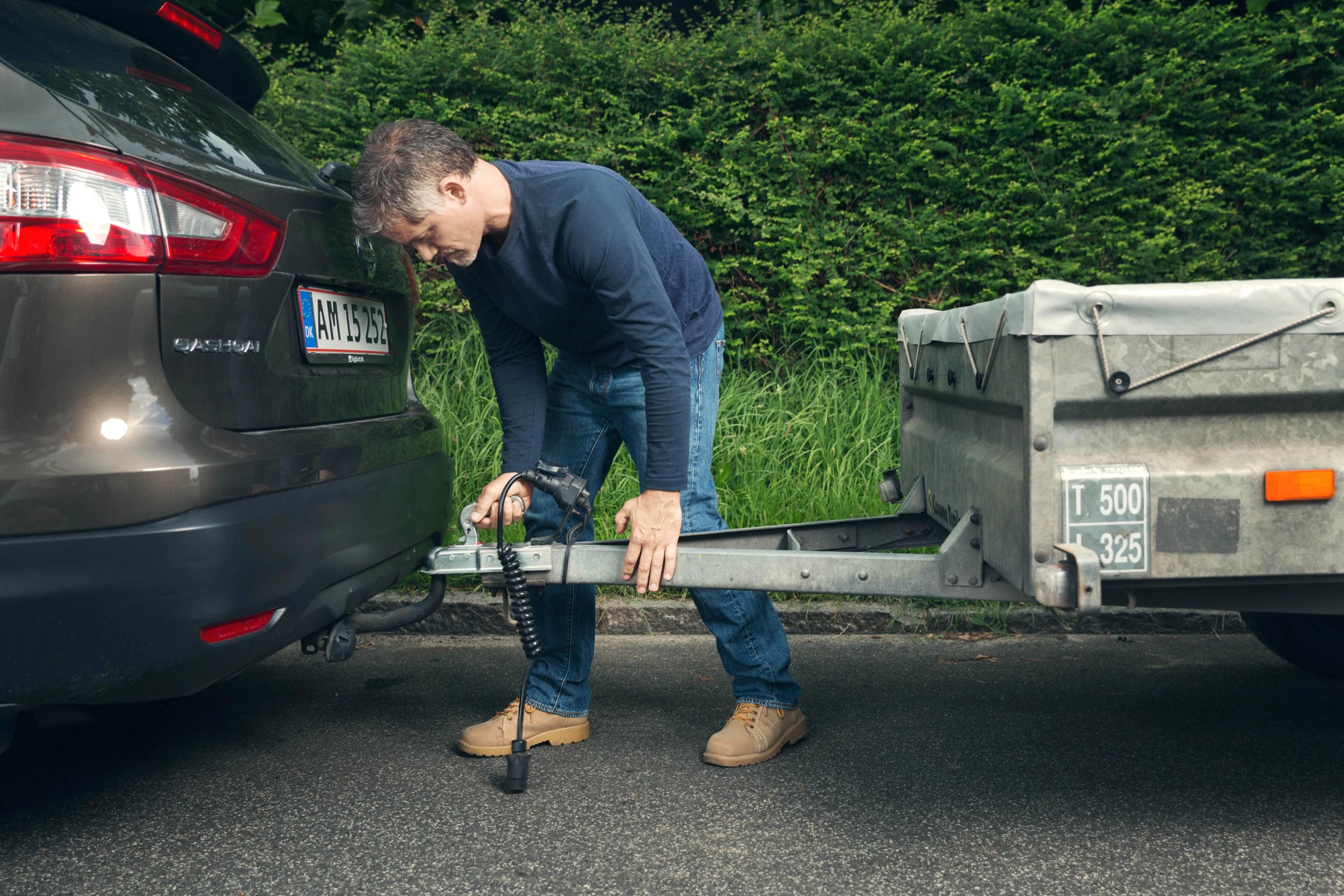 Mand kobler trailer til sin bil. 