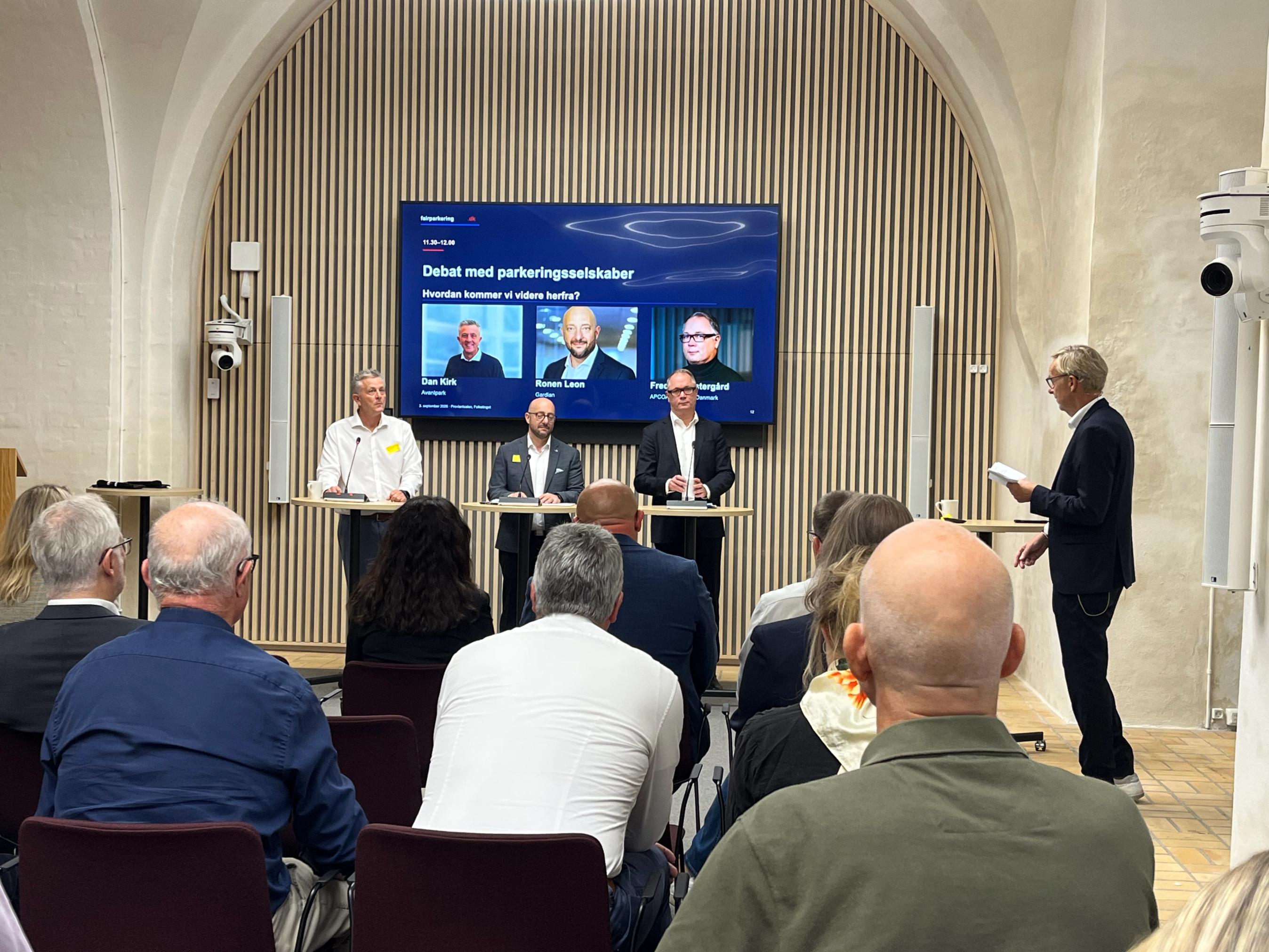 Tre mænd i paneldebat med ordstyrer