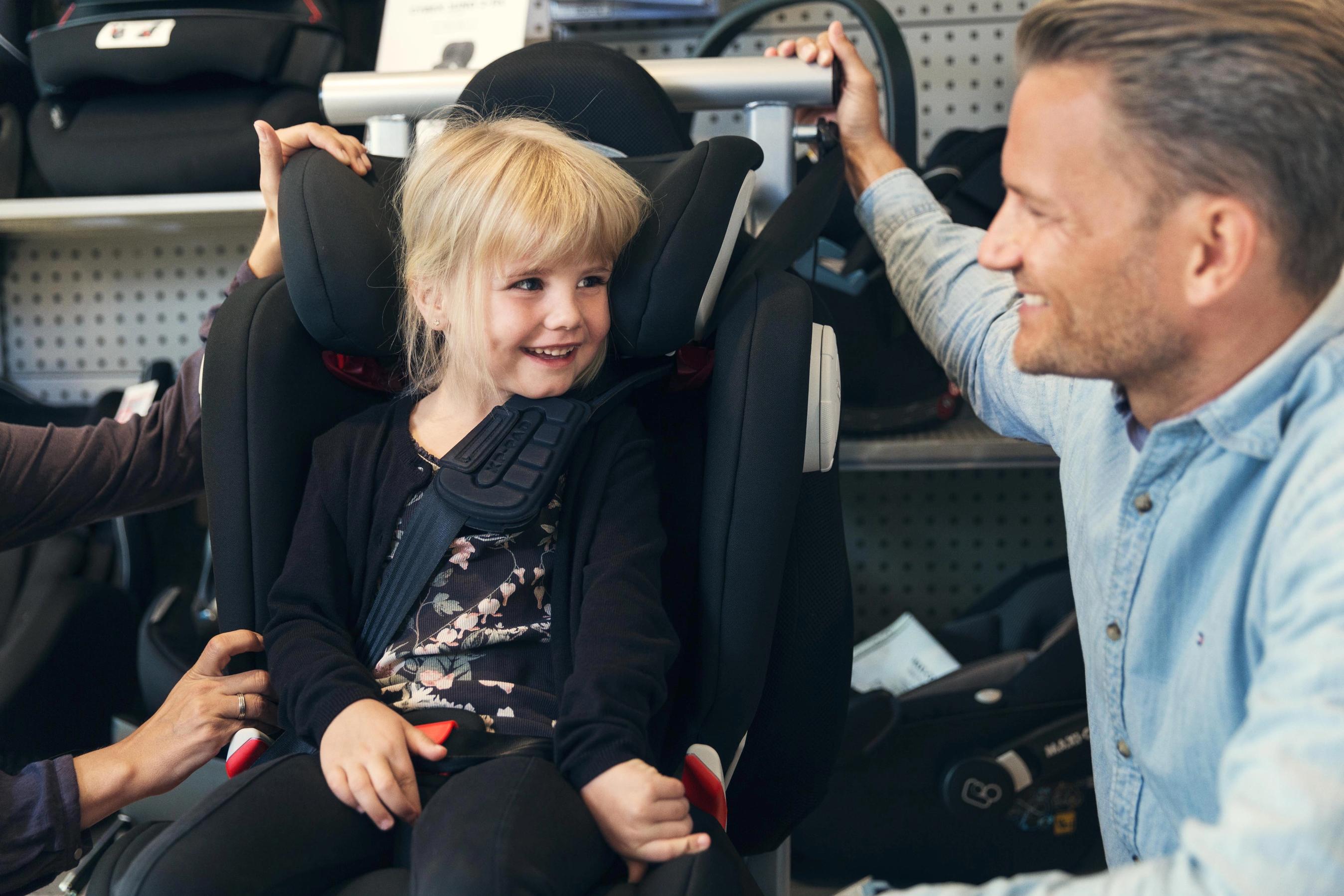 Barn prøver at sidde i en autostol i en butik inden køb.