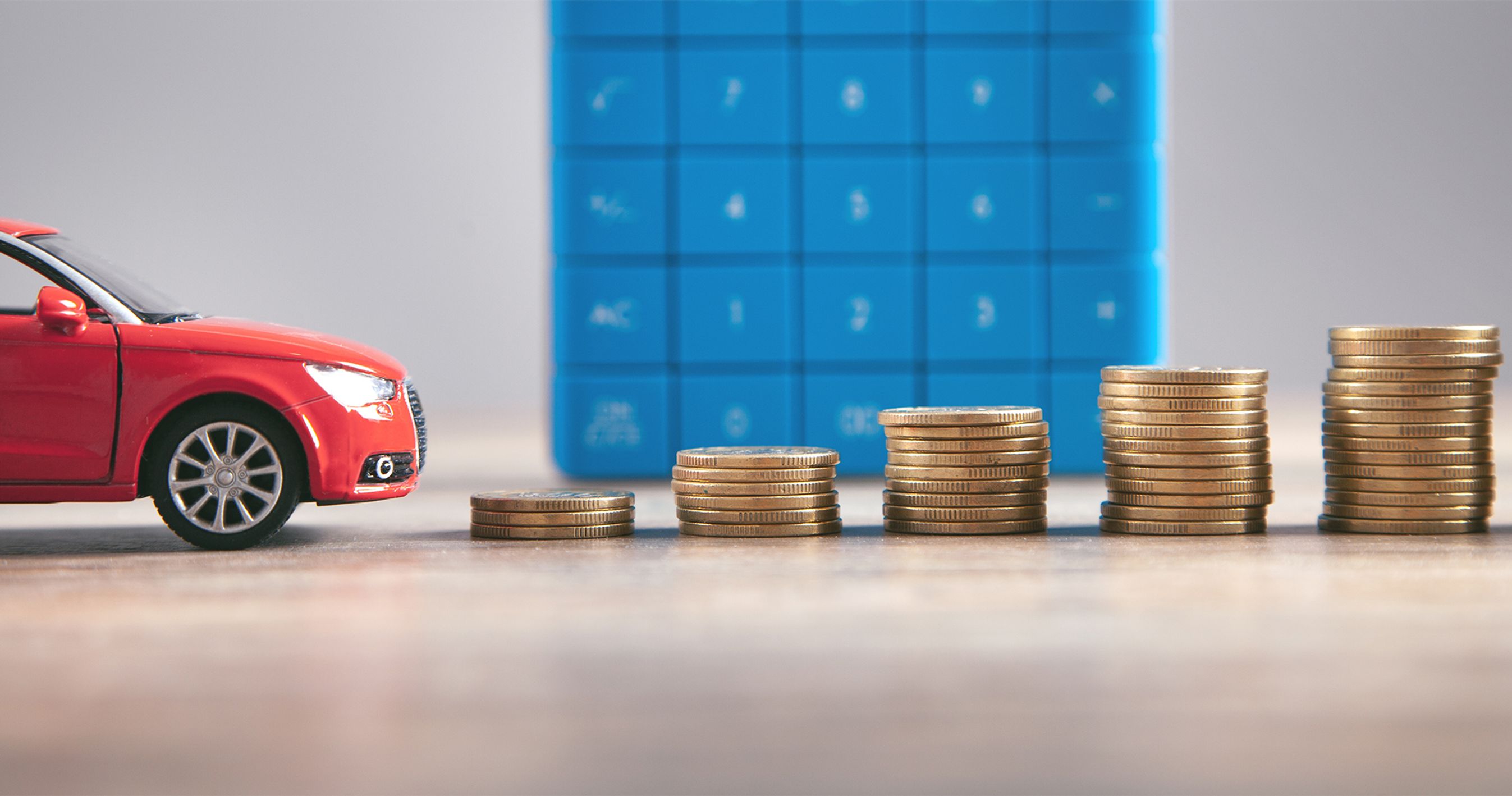 Rød legetøjsbil foran stabler af mønter