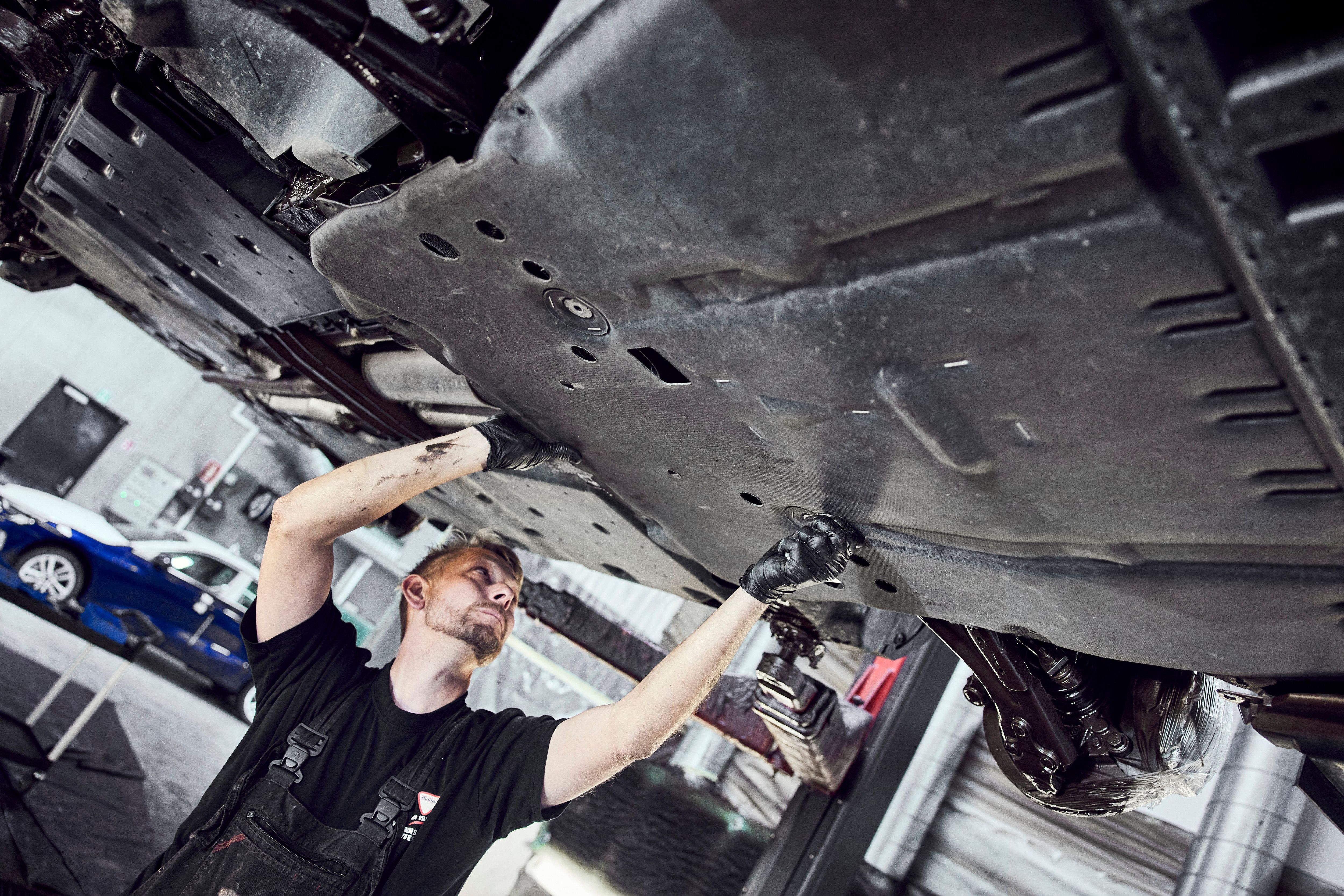 Mand står under hævet bil