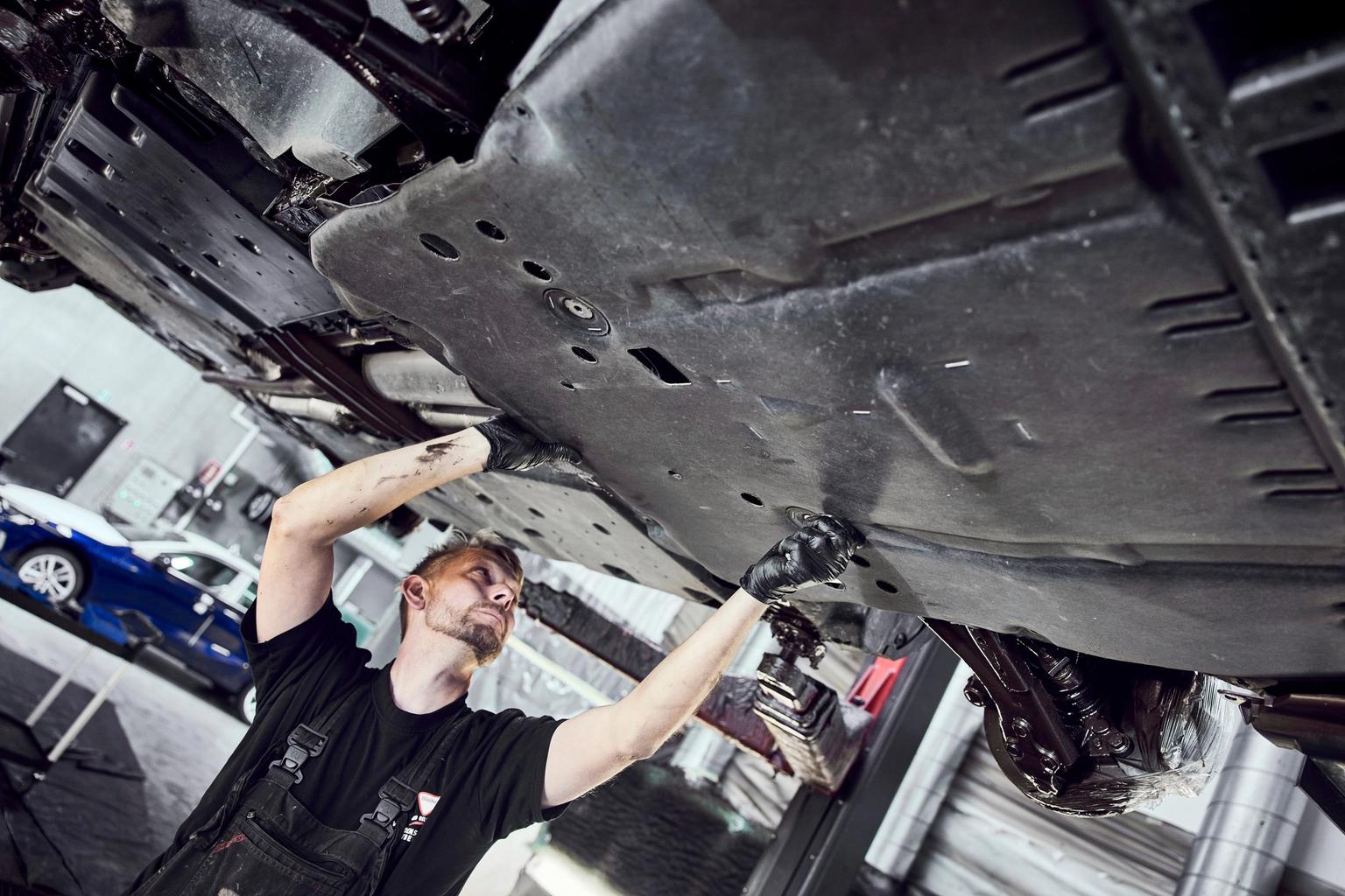 Mand står under hævet bil