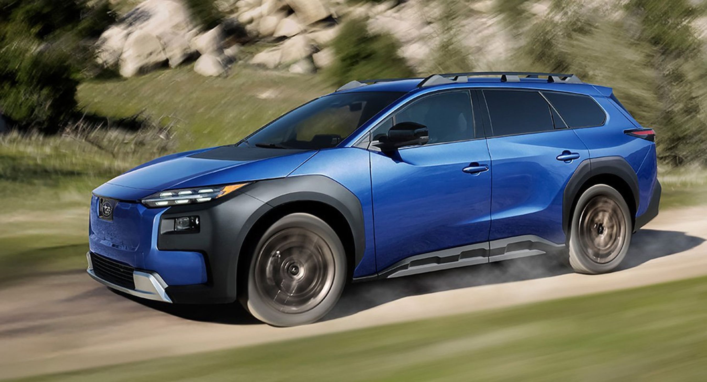 Blå E-Outback kørende på grusvej.