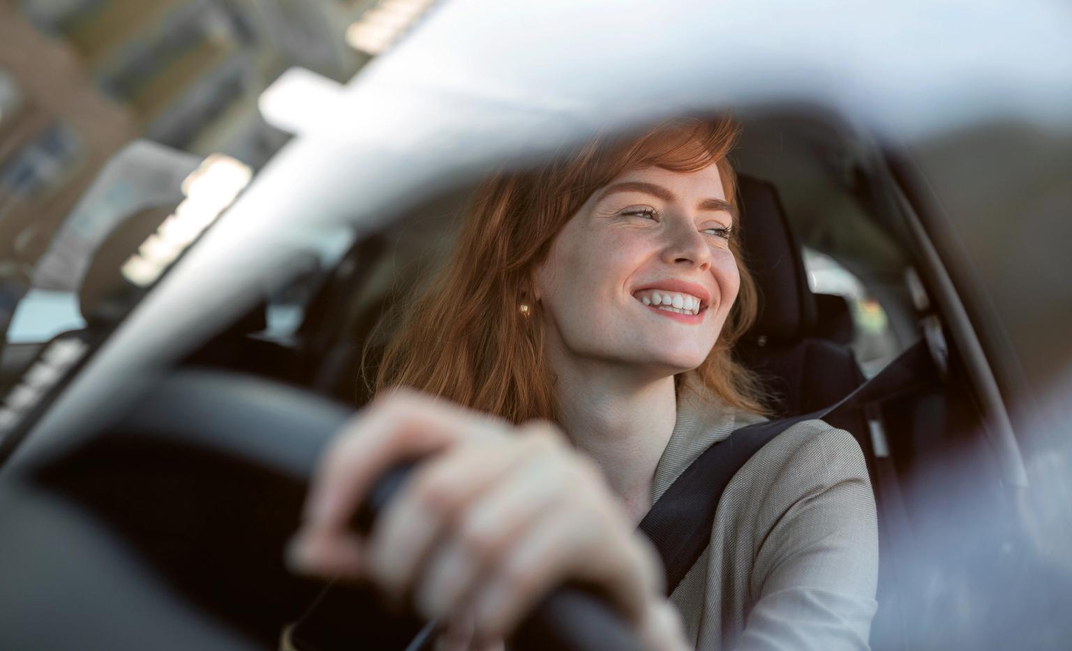 Kvinde smiler imens hun kigger ud af ruden