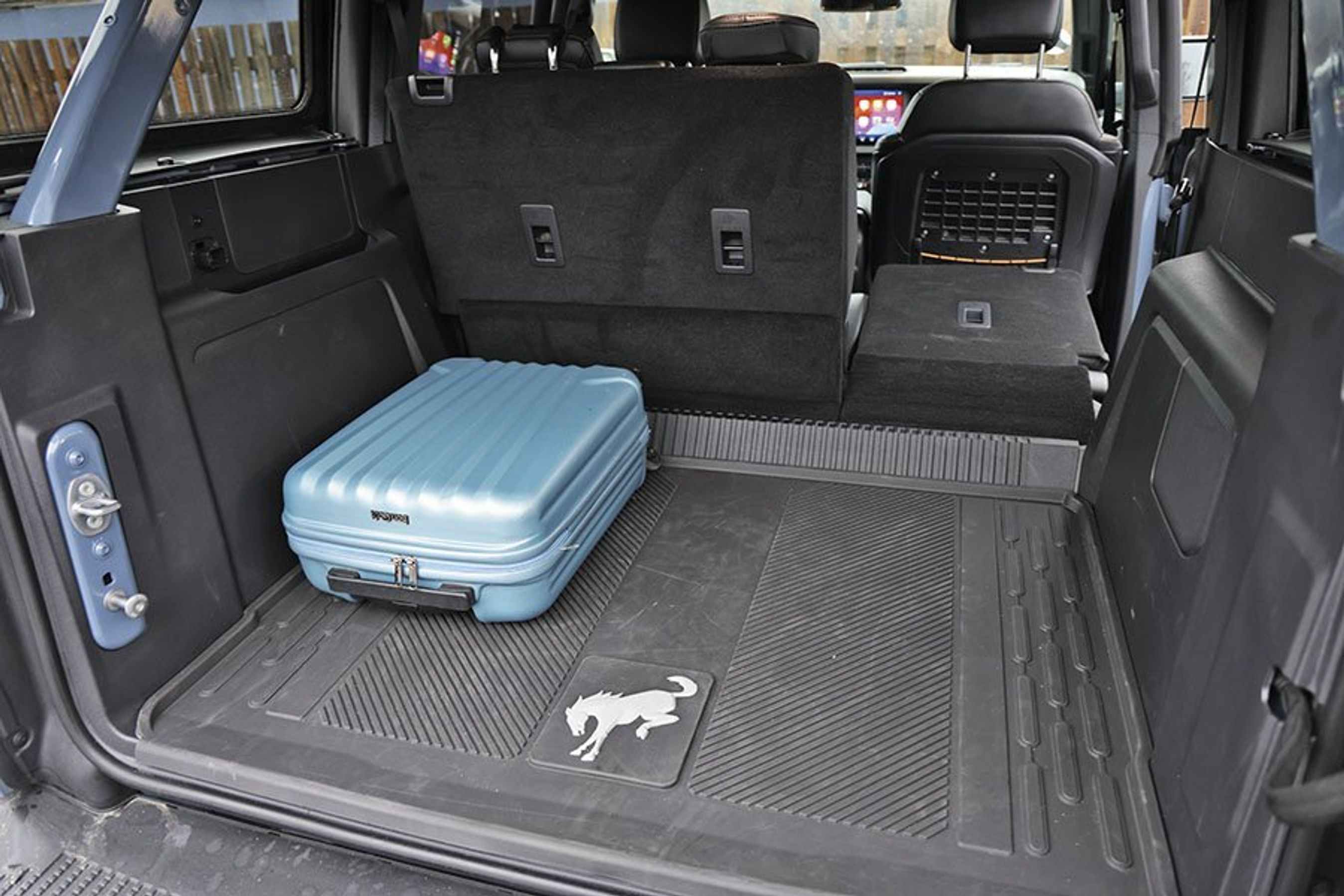 Bagagerum med blå kuffert i en Ford Bronco.