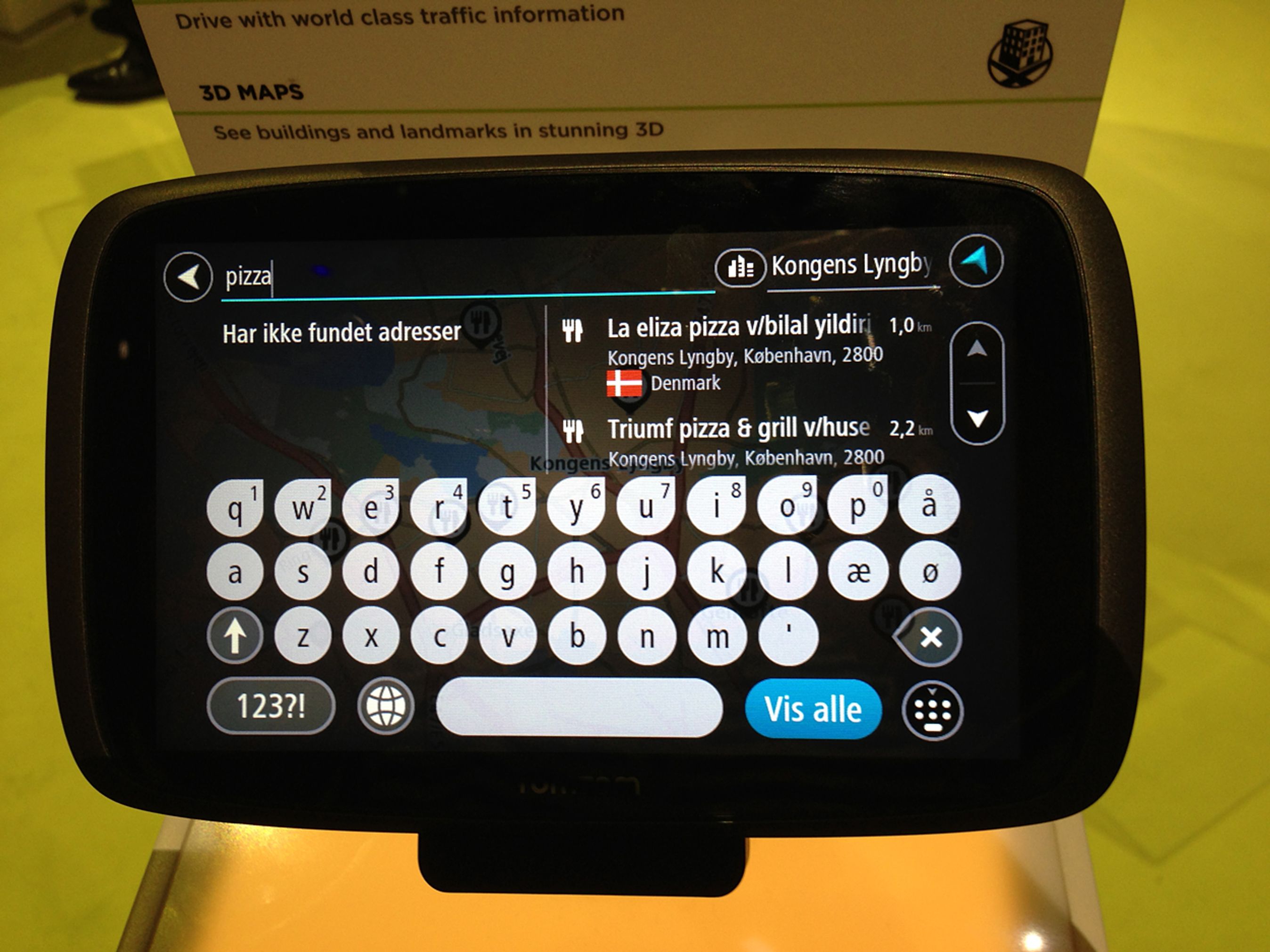 Du kan søge efter en adresse, enten ved at taste hele adressen ind eller blot at indtaste vejnavnet, byen eller postnummeret. Du kan også søge direkte efter noget konkret. Her har vi søgt efter Pizza omkring Lyngby, og da der ikke findes en Pizzavej i Lyngby, viser den en liste over restauranter med Pizza i navnet. TomTom har ikke stemmestyring af destinationen.