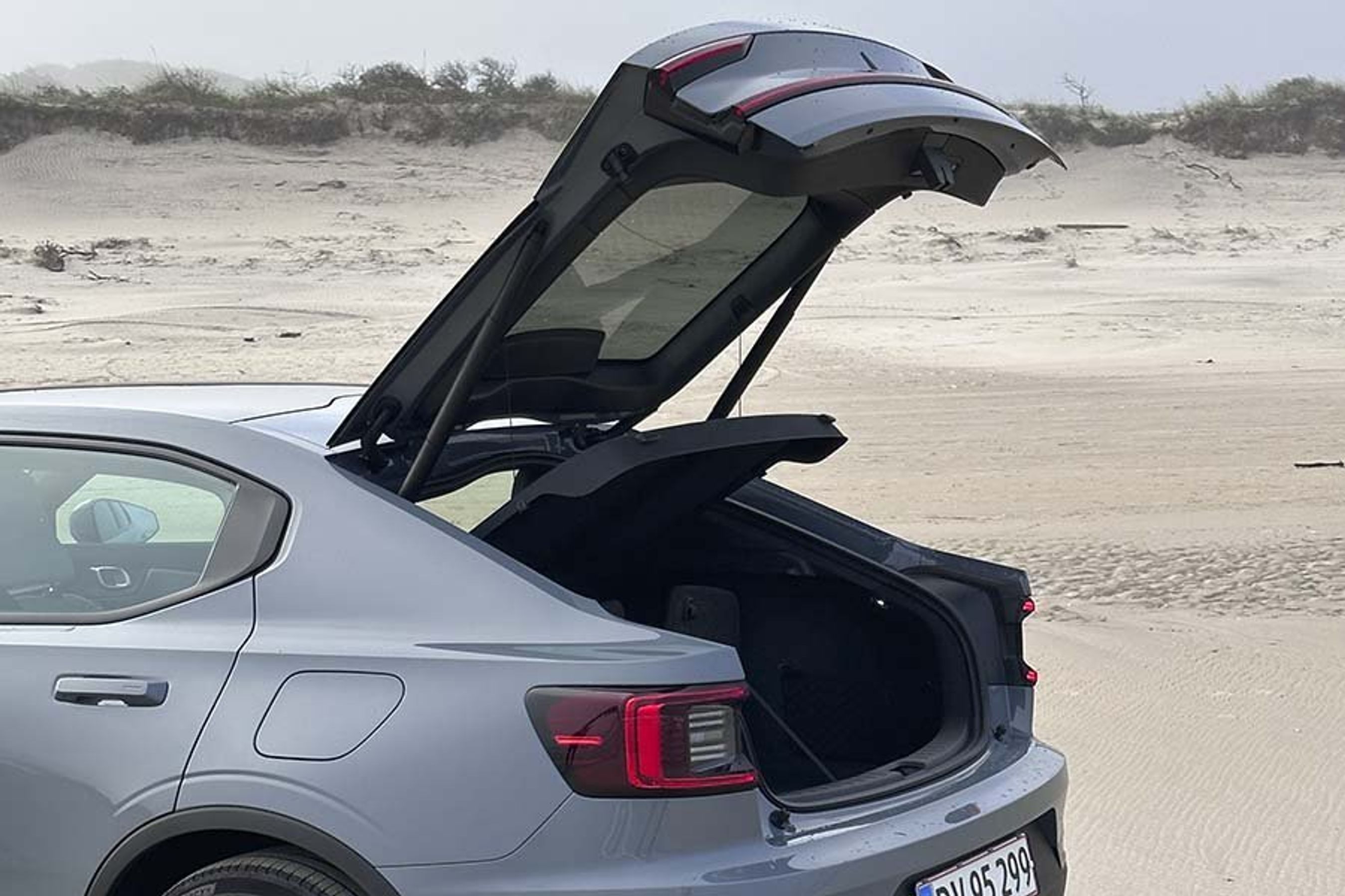 Stor bagklap giver god adgang til bagagerummet i Polestar 2, der holder på en strand