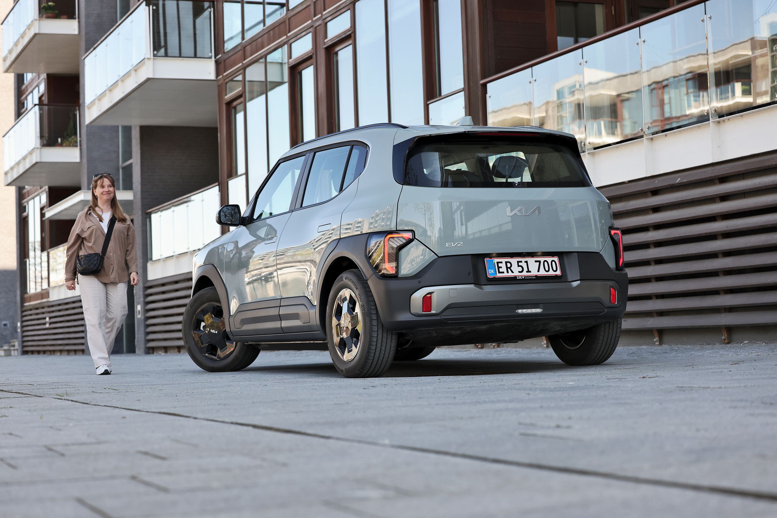 Kvinde går hen imod en Kia EV2, der holder med bagenden mod beskueren