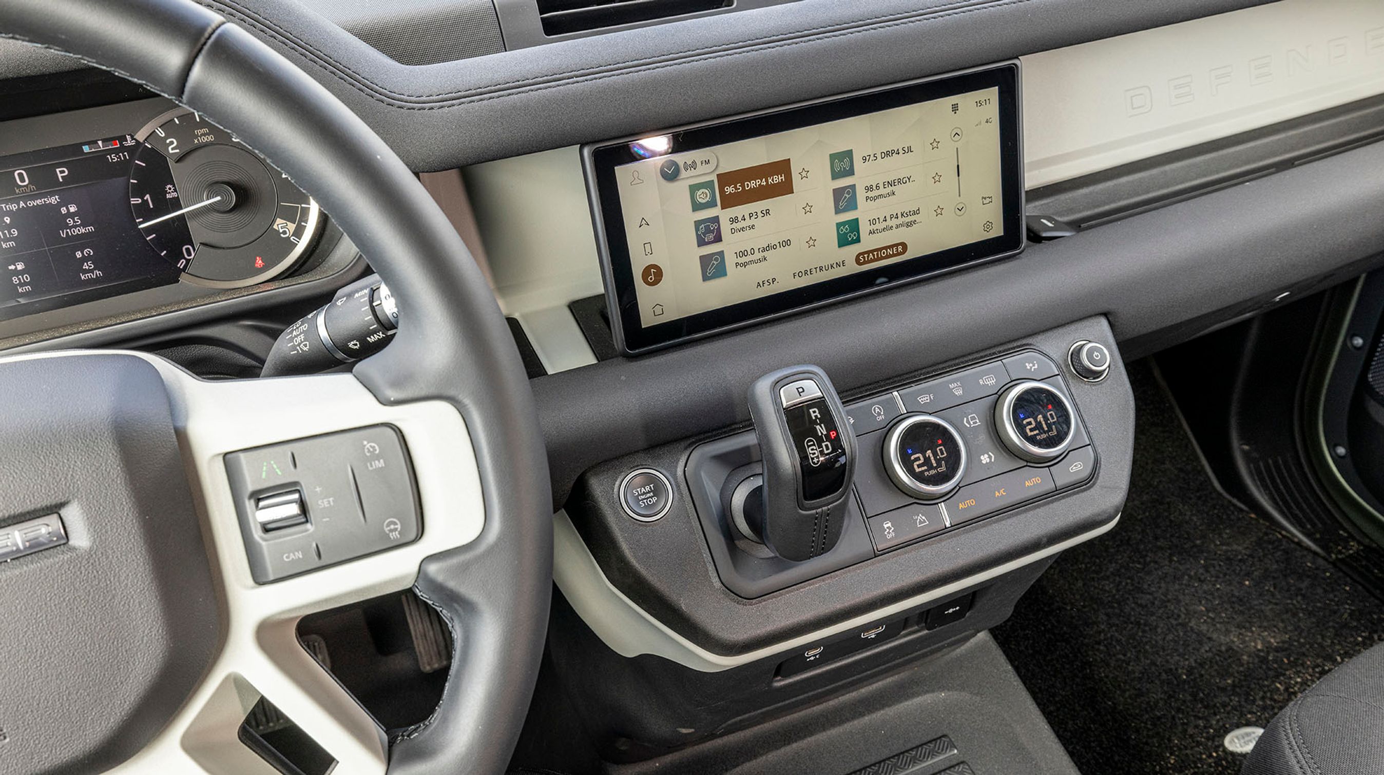 Defender fås kun med automatgear, der betjenes fra denne gearstang til højre fra rattet. Fra skærmen i midten styres radio, navigationsanlæg og lignende. Det fungerer ganske glimrende, og der er danske menuer, som man let kan bladre igennem.