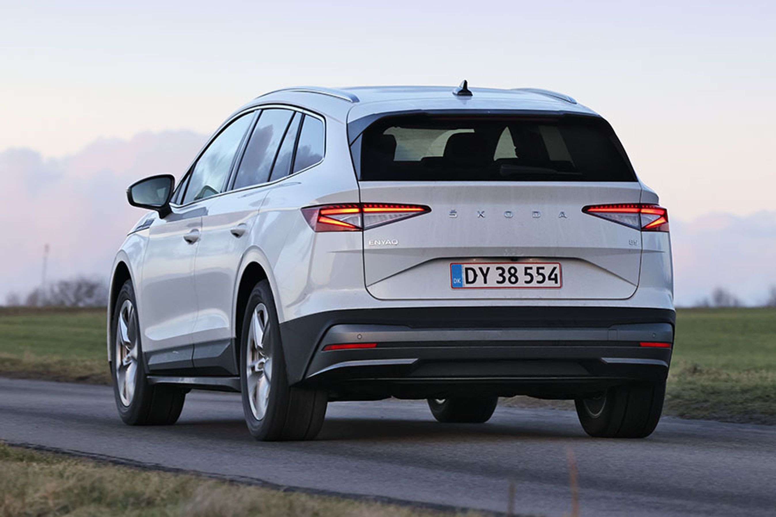 Skoda Enyaq set bagfra, mens den kører på en landevej i tusmørke