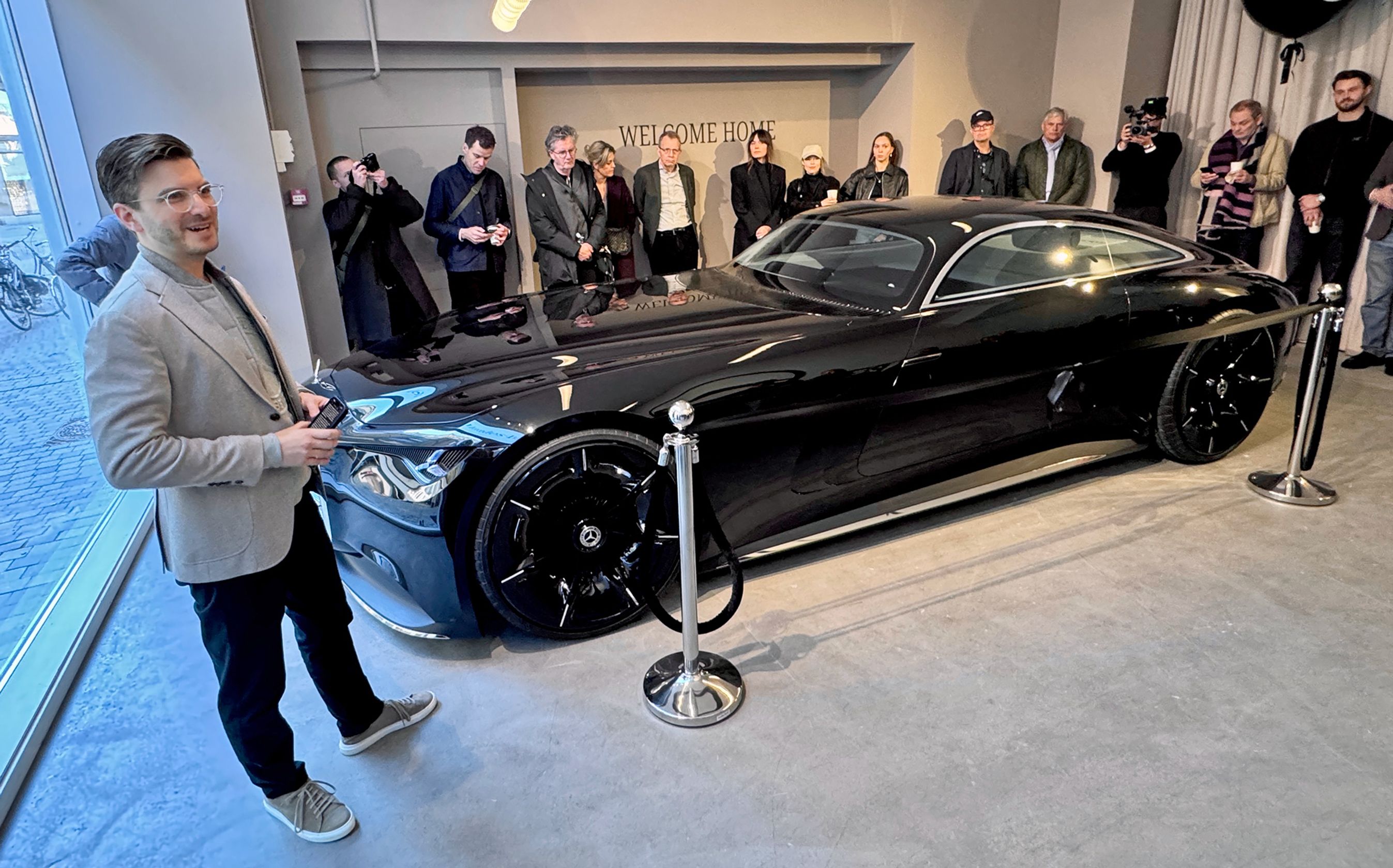 Mand holder tale foran meget lang sort bil.